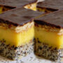 Prăjitură cu blat cu mac, cremă de vanilie si glazură de ciocolată tăiată în bucăți dreptunghiulare și așezată pe un blat de bucătărie gri