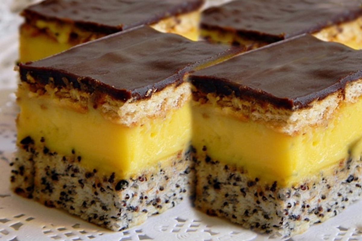 Prăjitură cu blat cu mac, cremă de vanilie si glazură de ciocolată tăiată în bucăți dreptunghiulare și așezată pe un blat de bucătărie gri