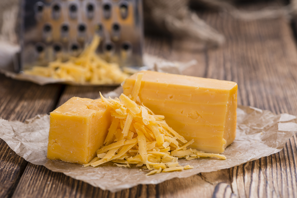 Brânză cheddar cu maturație emdie pe un tocător de lemn