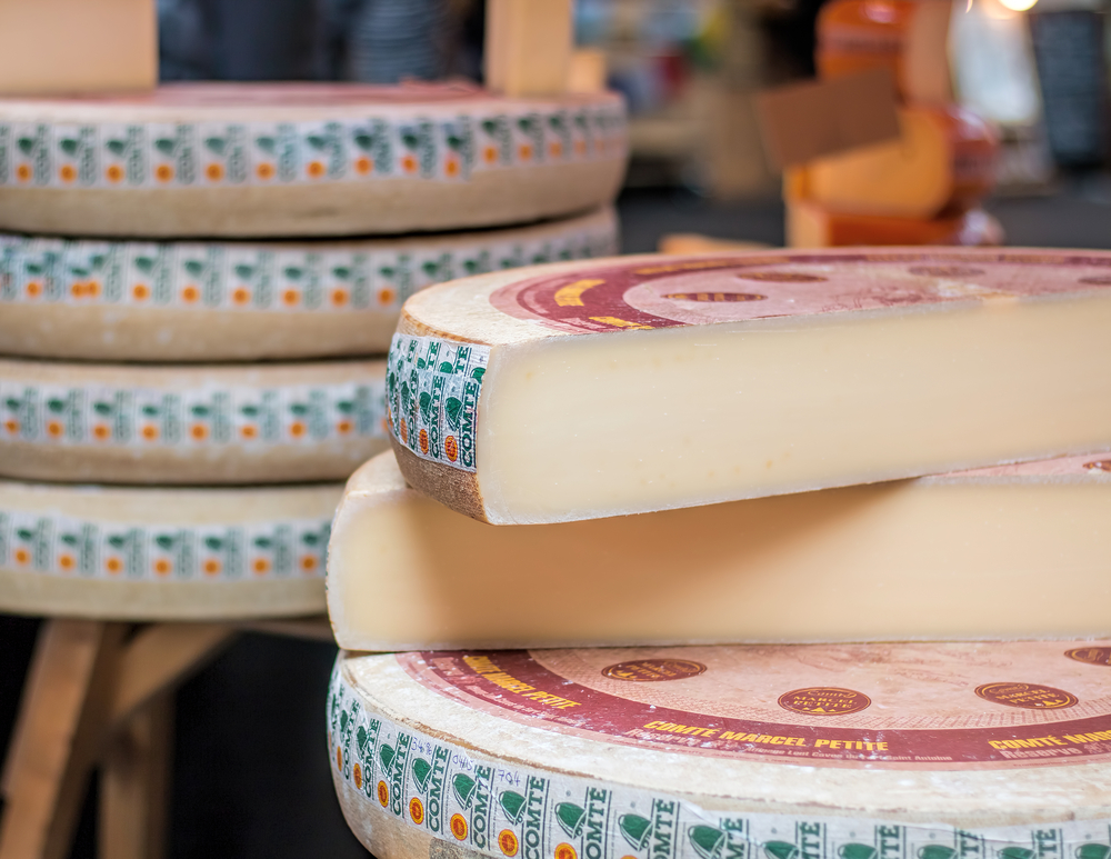 Mai multe jumătăți de brânză comte aranjate una peste alta