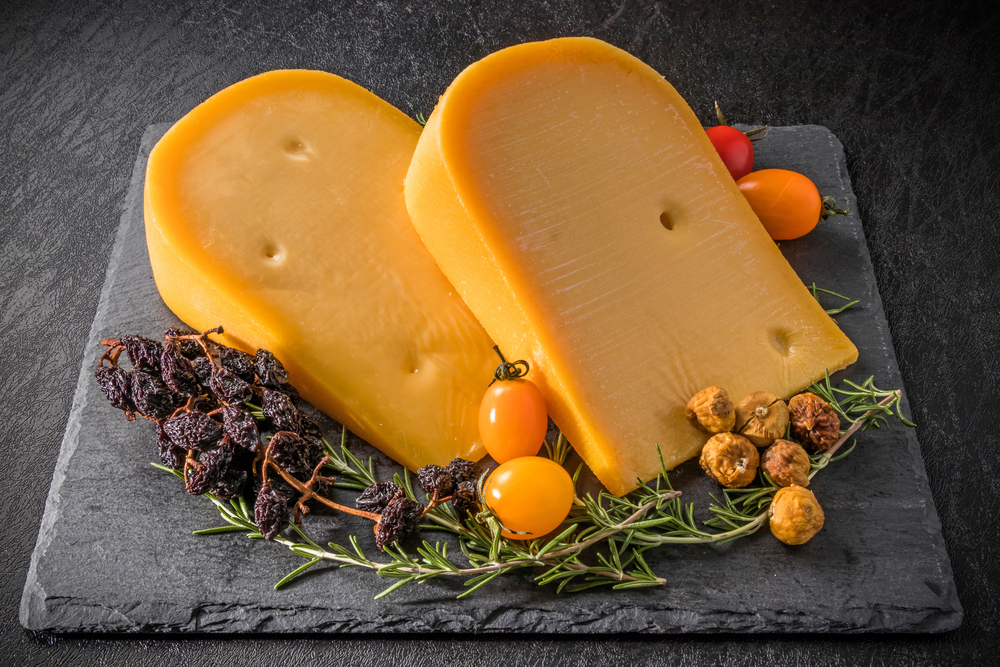 Două bucăți mari de brânză gouda pe un platou gri