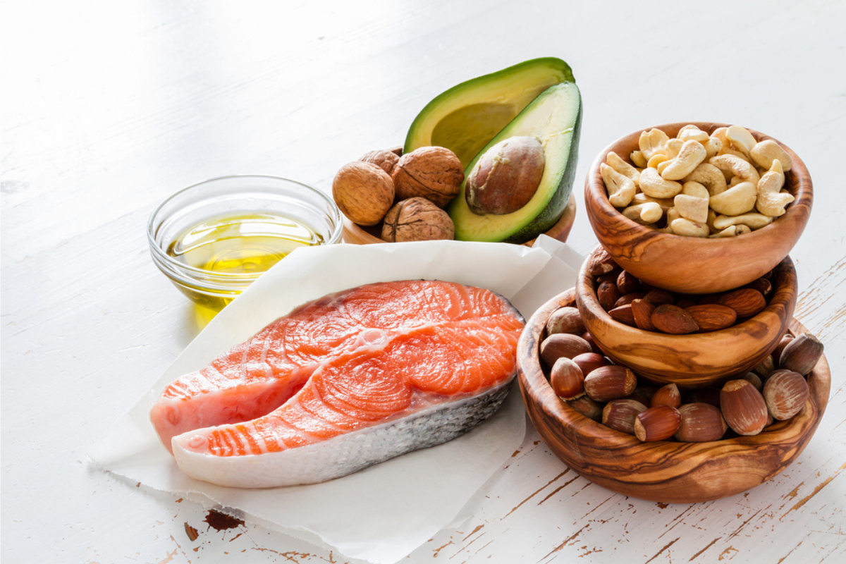 Mai multe alimente care te ajută să reduci colesterolul puse pe o masă albă