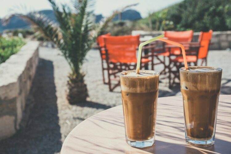 Caffe Frappe, într-un pahar din sticlă, pe o masă de pe plajă