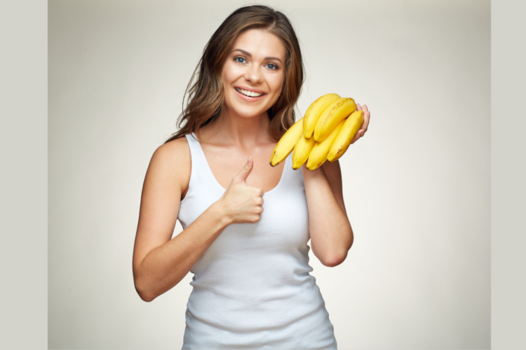O femeie veselă cu un mănunchi de banane în mână