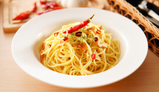 Spaghete aglio e olio într-o farfurie adâncă, decorate cu ardei iute roșu