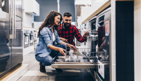 Un cuplu se află în bucătărie și pune vesela într-o mașină de spălat vase.
