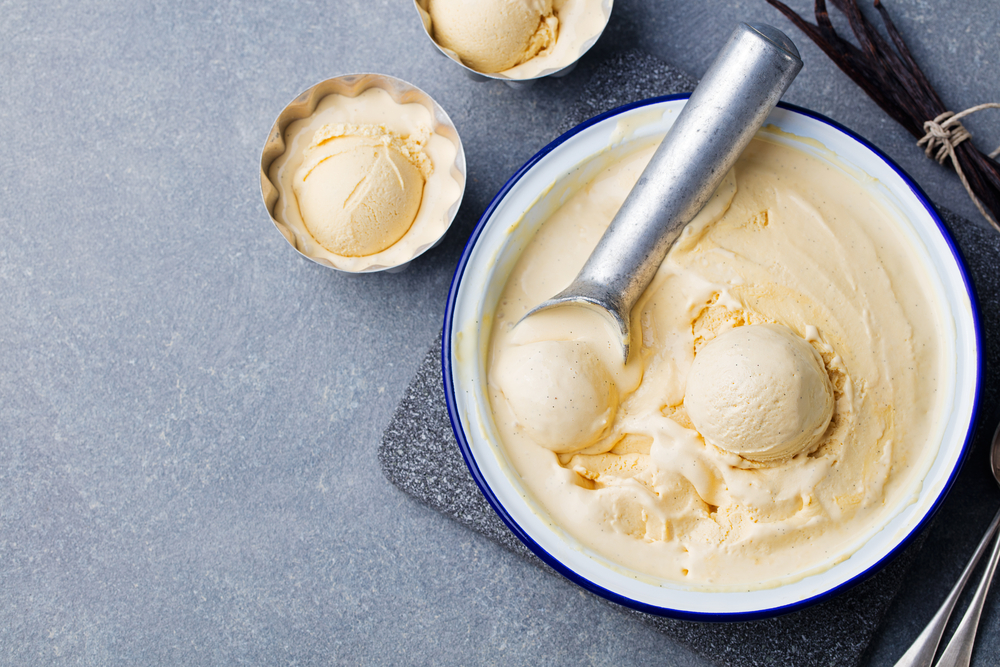 Înghețată de casă cu aromă de vanilie, alături de o cupă metalică pentru servit desertul.
