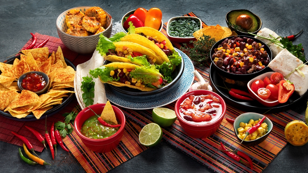 Sosurile mole pe o masă de lemn alături de mai multă mâncare mexicană