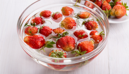 Căpșuni, într-un bol transparent, plin cu apă