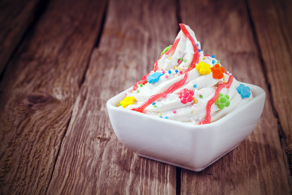Înghețată de iaurt decorată cu biluțe de zahăr și servită într-un bol alb