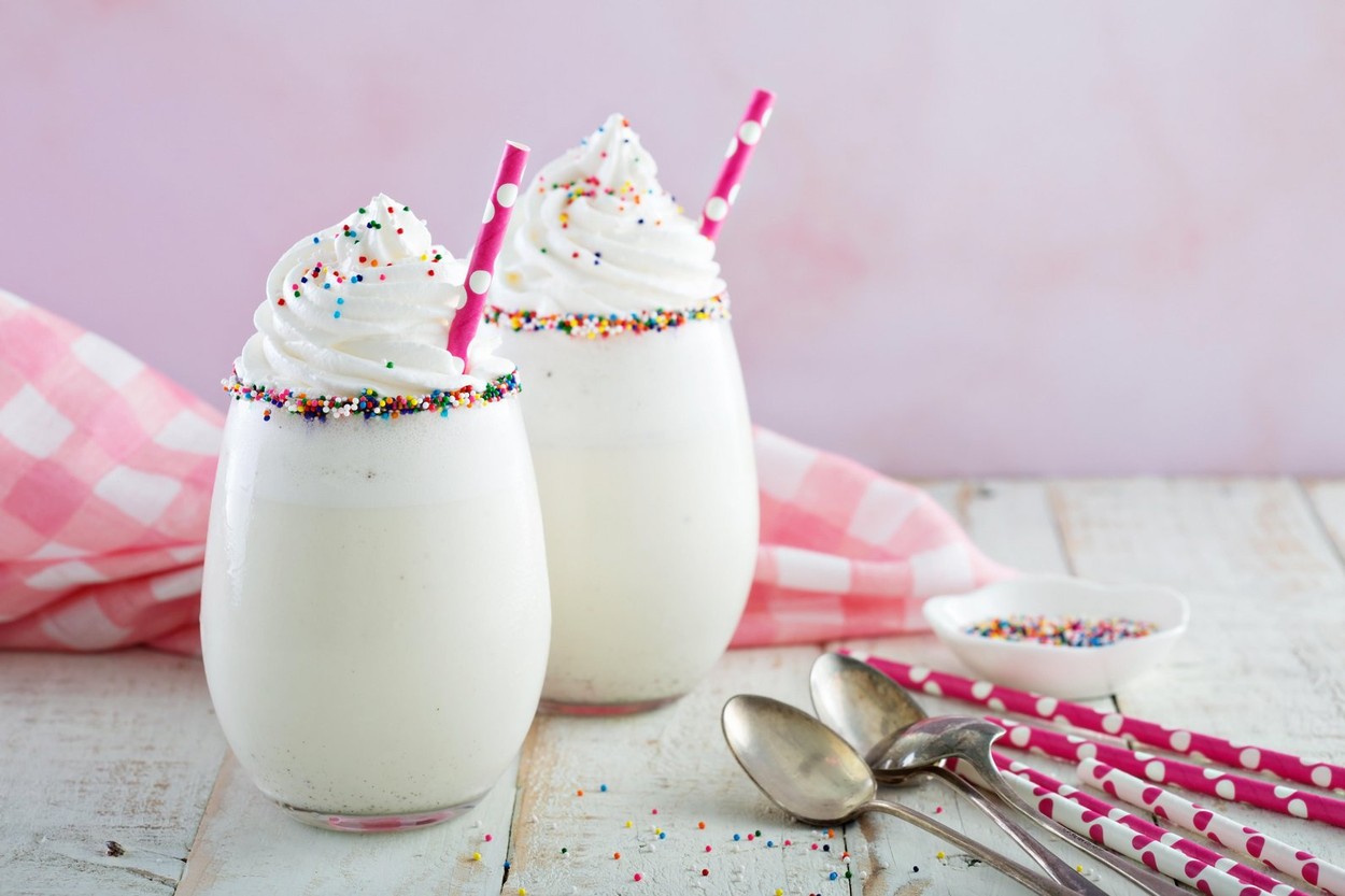 Un pahar de milkshake cu vanilie, decorat cu bomboane