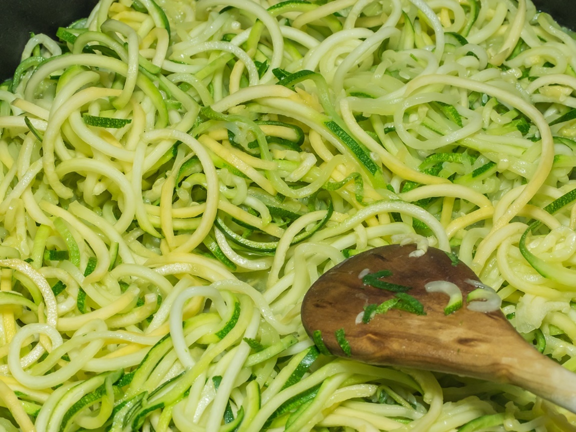 Amestecarea spaghetelor de dovlecei în tigaia cu ulei înfierbântat