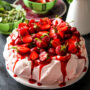 O prăjitură pavlova, decorată cu căpșuni și sos de coacăze roșii