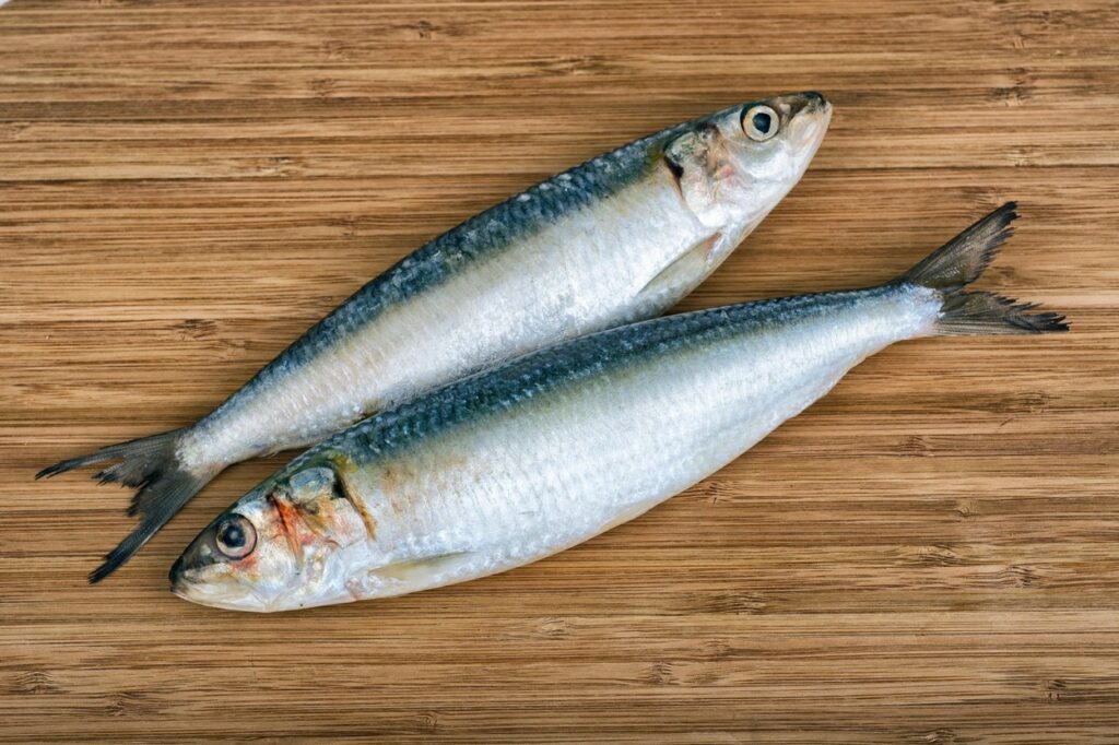 Două sardine care stau aranjate pe un blat de lemn