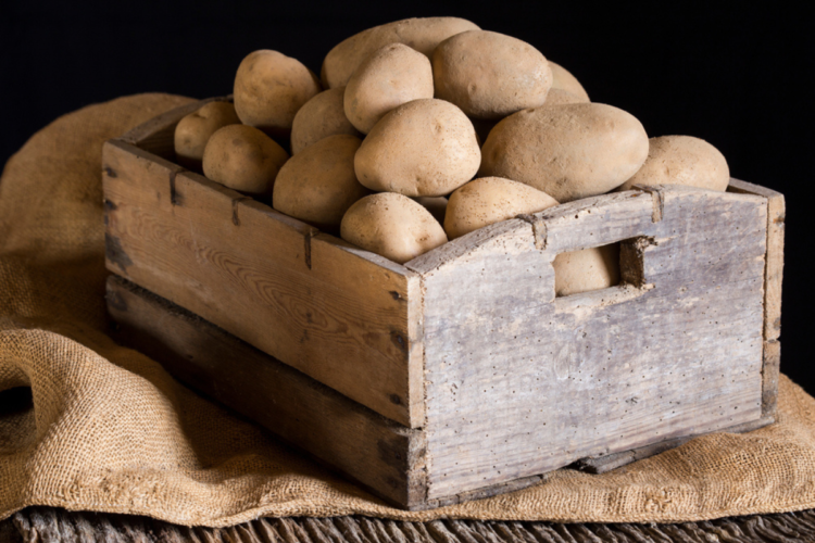 O cutie de lemn plină de cartofi care îți arată cum poți păstra cartofii 6 luni