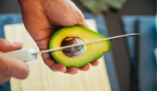Un bărbat care folosește un cuțit de metal pentru a tăia avocado