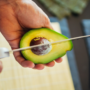 Un bărbat care folosește un cuțit de metal pentru a tăia avocado