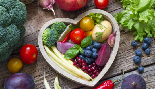Un vas în formă de inimă în care se află alimente care ajută la reducerea colesterolului