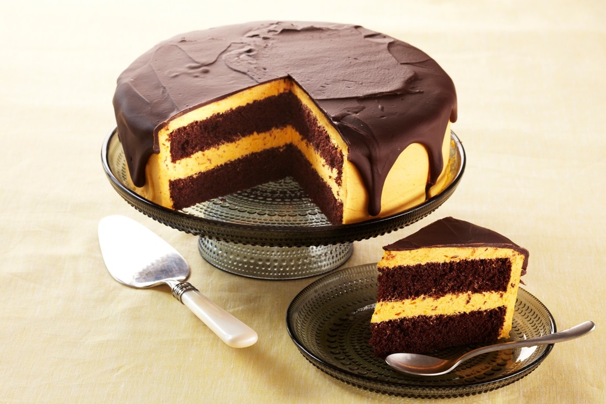Tort cu cremă de dovleac copt și glazură de ciocolată secționat pe un platou cu picior și o felie de tort pe farfurie