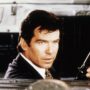 Pierce Brosnan în rolul lui James Bond în timp ce se află într-o mașină și ține în mână un pistol