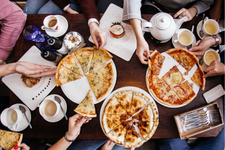O masă pe care se află mai multe feluri de pizza pentru a ilustra ce să nu comanzi niciodată de la o pizzerie