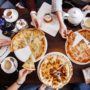 O masă pe care se află mai multe feluri de pizza pentru a ilustra ce să nu comanzi niciodată de la o pizzerie