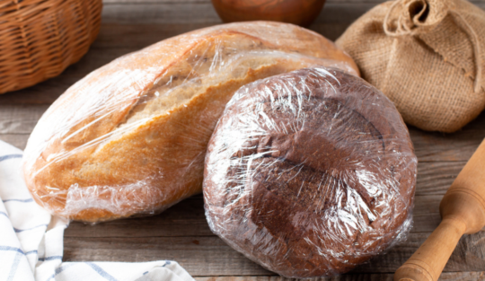 O masă pe care se află două pâini împachetate după o metodă despre cum să păstrezi pâinea proaspătă