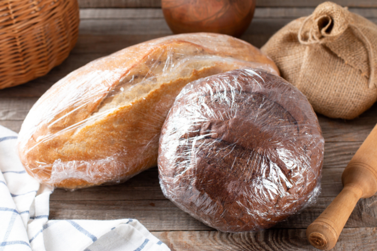 O masă pe care se află două pâini împachetate după o metodă despre cum să păstrezi pâinea proaspătă