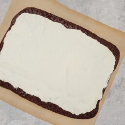 Foaie de ruladă cu cacao în compoziție, peste care este întinsă cremă de ciocolată albă