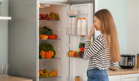 O femeie care se uită într-un frigider fără curent electric