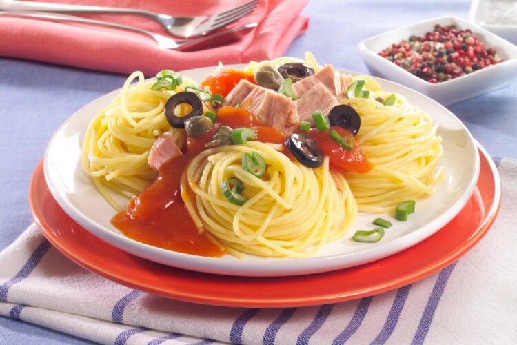 Porție de spaghete cu ton și sos de roșii pe un set de două farfurii, una albă și una roșie