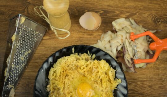 Cartofi răzuiți într-un bol și amestecați cu ouă