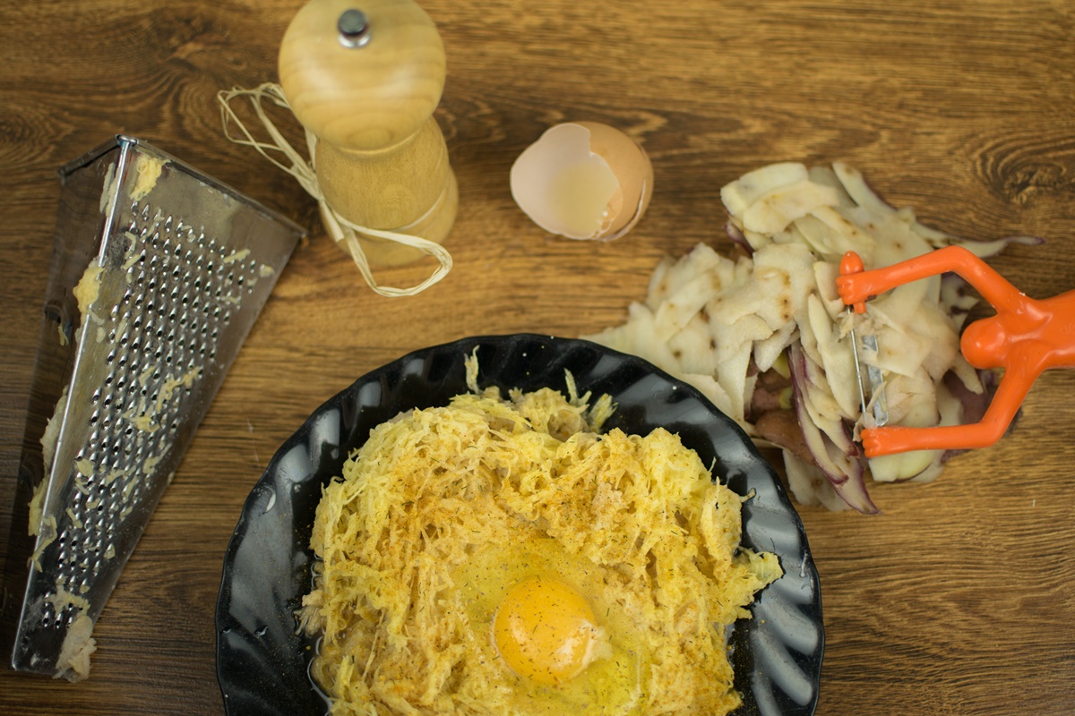 Cartofi răzuiți într-un bol și amestecați cu ouă