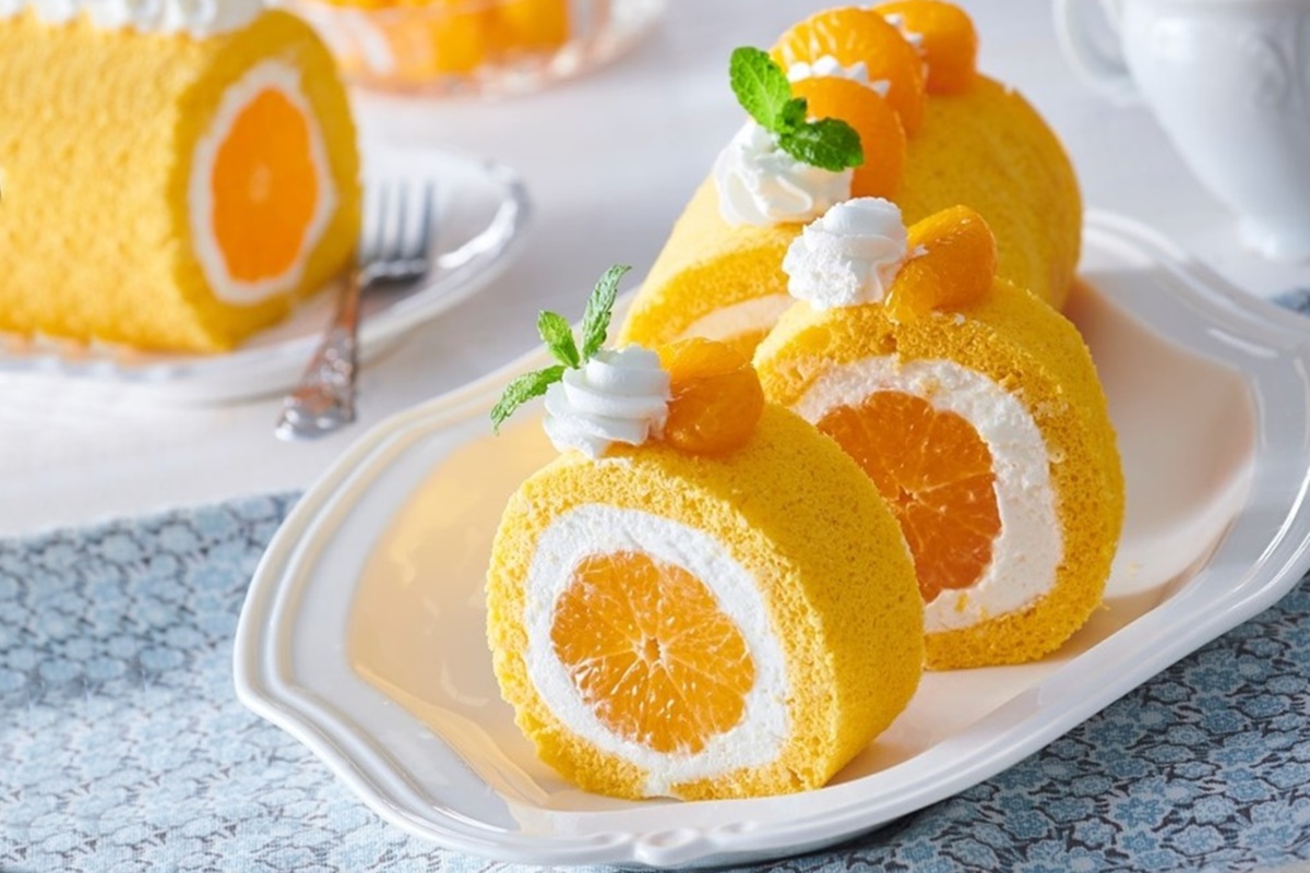 Ruladă cu portocale întregi și cremă de mascarpone porționată pe un platou alb