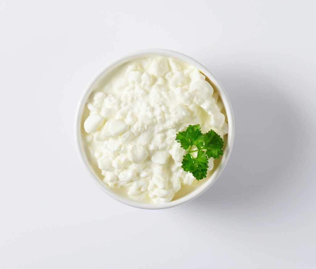 Brânză cottage pusă într-un bol alb și decorată cu pătrunjel