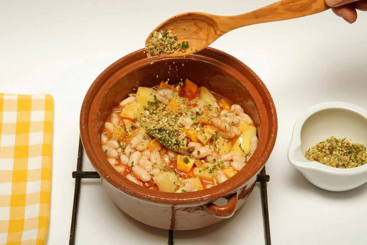 fasole cu legume și condimente în bol ceramic cu lingură de lemn
