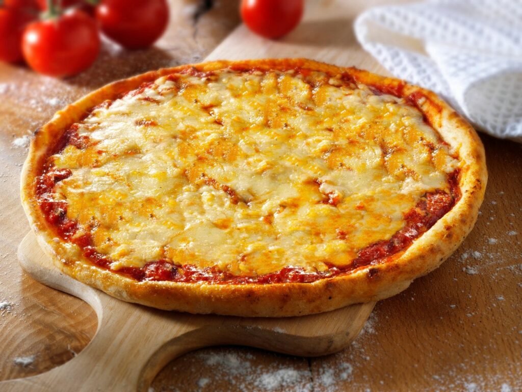 Pizza cu brânză pe un blat de lemn alături de un ștergar