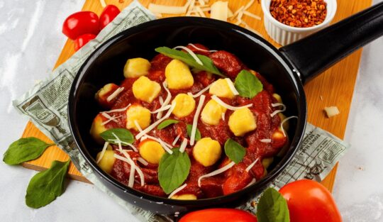 Tigaie cu sos de roșii preparat și amestecat cu gnocchi de cartofi