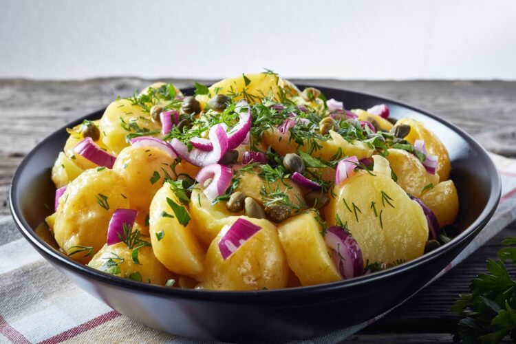 Salată de cartofi cu ceapă roșie în bol negru