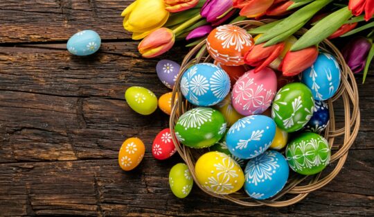 Ouă rmase de la Paște așezate într-un coș de lemn și alături de un buchet de lalele