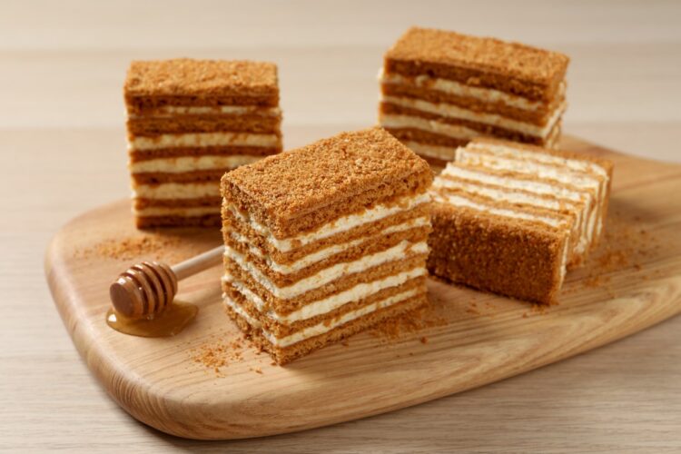 Patru porții de prăjitură cu foi cu miere și cremă de mascarpone cu ciocolată albă pe un platou de lemn