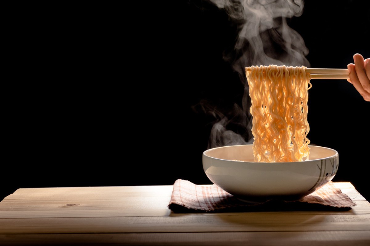 Ghidul tăiețeilor chinezești ilustrat cu ajutorul unui bol în care se toarnă tăieței chinezești fierbinți