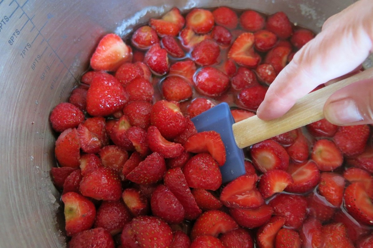 Femeie amestecând în cratița cu căpșuni pentru gem
