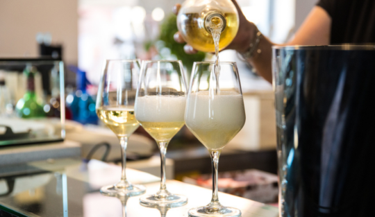 Diferența dintre prosecco și șampanie ilustrată cu ajutorul unor pahare în care se toarnă băutura spectaculoasă