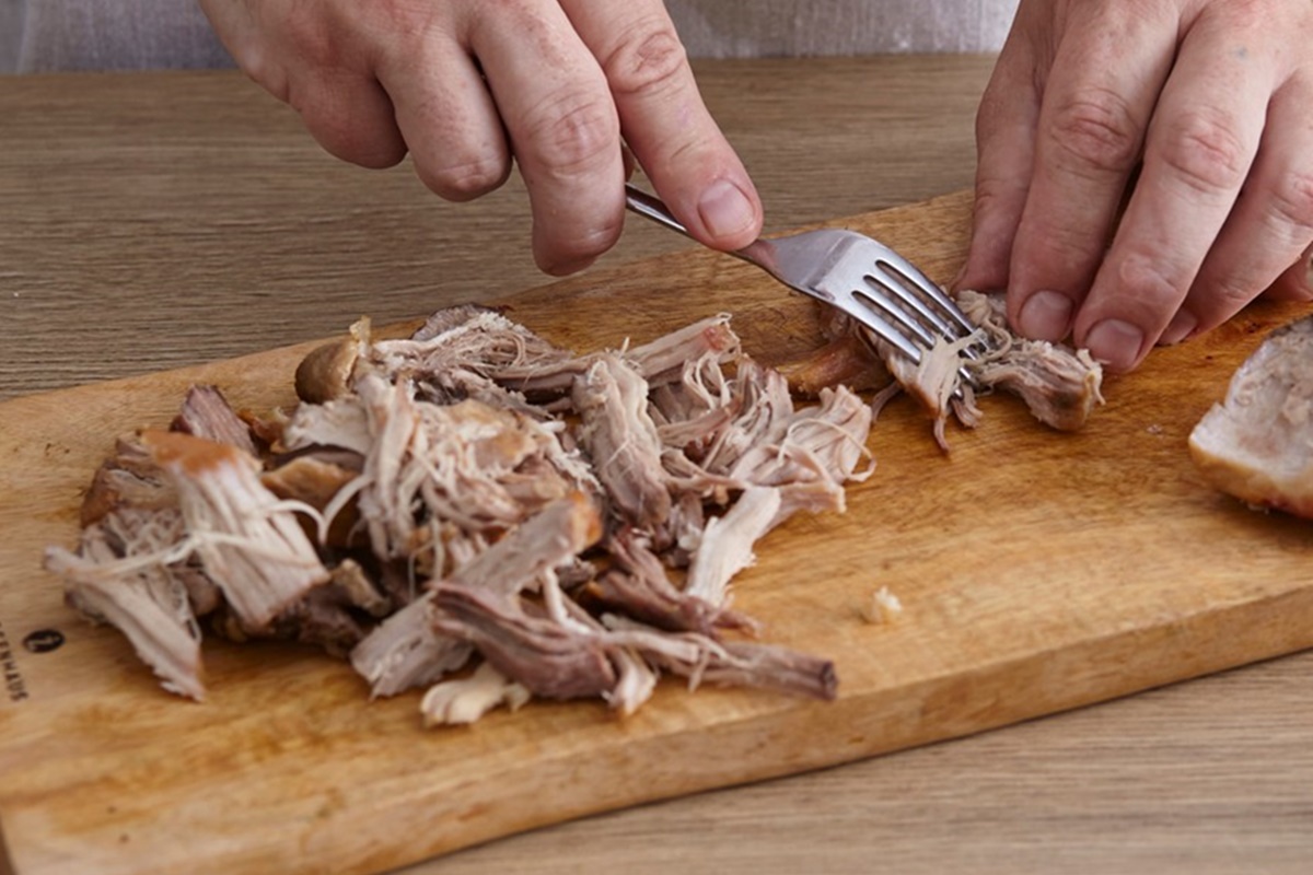 Carnea se desface în franjuri cu furculița pe un tocător