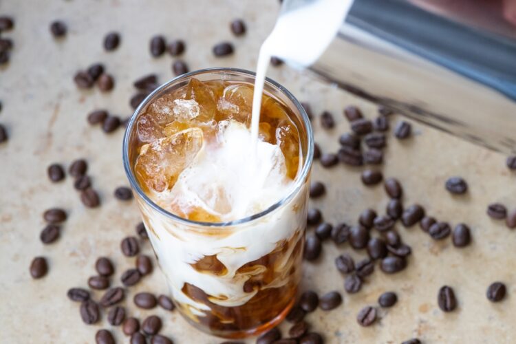 Lapte turnat într-un pahar cu cafea înghețată