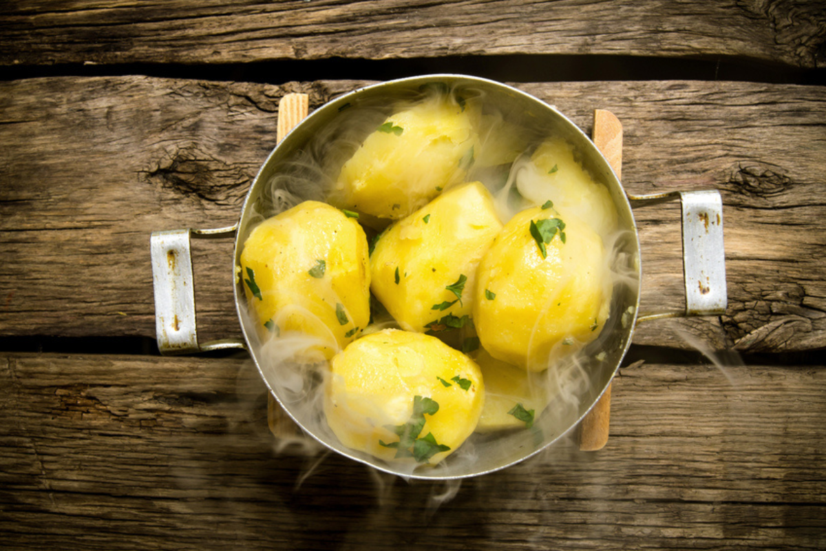 Cel mai sănătos mod de a găti cartofii ilustrat cu ajutorul unei oale în care se află cartofi la fiert