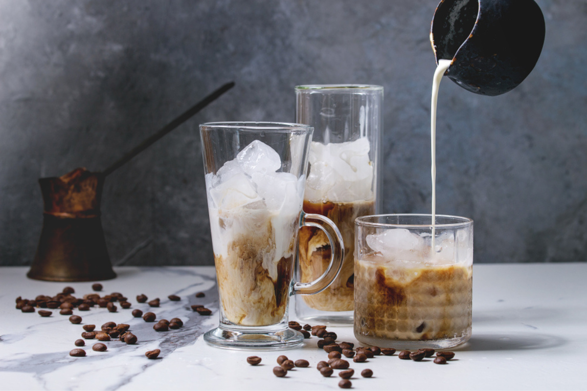 Rețete de ice coffee ilustrate cu ajutorul a trei pahare pline cu această băutură