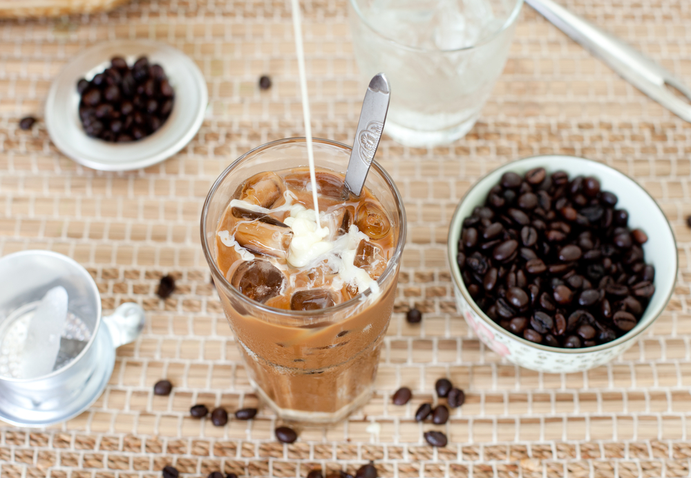 Ice Coffee servită cu lapte, alături de un bol plin cu boabe de cafea