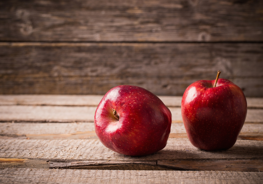 Două mere Red Delicious pe un blat de lemn